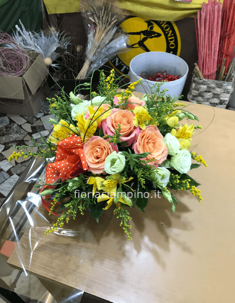 Cestino di vimini o ciotola di ceramica, composto da rose e verde pregiato.